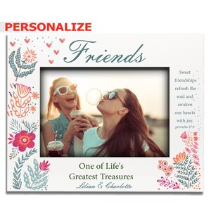 May include: A white photo frame with a floral design border. The frame has a photo of two friends laughing and blowing a bubble. The text "Friends" is at the top of the frame. The text "One of Life's Greatest Treasures" is at the bottom of the frame. The text "Lilian & Charlotte" is below the text "One of Life's Greatest Treasures".