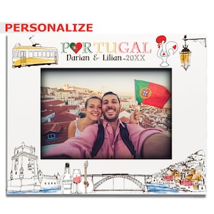 May include: A white photo frame with a red heart and the word "PORTUGAL" in colorful letters. The frame has a picture of a couple taking a selfie in front of a city skyline. The frame also has a red rooster, a yellow tram, and a bridge.