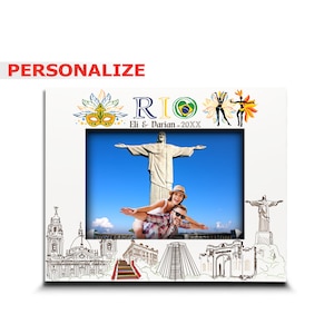 May include: A white photo frame with a picture of a couple in front of the Christ the Redeemer statue in Rio de Janeiro, Brazil. The frame has a colorful border with the word "RIO" and the text "Eli & Darian - 20XX".