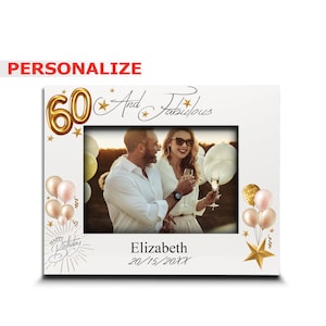 May include: A white photo frame with a gold 60 and the words "And Fabulous" in gold script. The frame has a picture of a couple toasting with champagne glasses. The frame also has gold stars and balloons. The text "Elizabeth 20/15/20XX" is at the bottom of the frame.