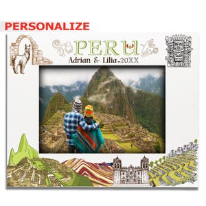 May include: A white rectangular picture frame featuring illustrations of a llama, ancient ruins, and the text PERU, Adrian & Lilia-20XX. The center displays a photograph of two people overlooking the Machu Picchu mountain landscape.