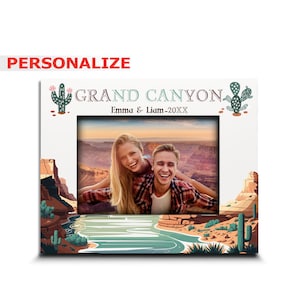May include: A personalized photo frame with a Grand Canyon landscape design. The frame features a couple smiling in front of the Grand Canyon. The text "Grand Canyon" is written in a decorative font with a cactus graphic on either side. The text "Emma & Liam - 20XX" is written below the "Grand Canyon" text.