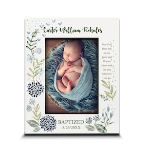 May include: White picture frame with a baby photo. The frame is decorated with blue and green floral designs and the text "Carter William Rokales" and "Baptized 5/25/20XX". The frame also includes the text "May God bless you as you grow and fill your heart with His love wherever you go."