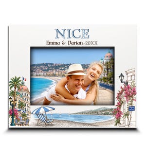 May include: A white rectangular picture frame featuring the text NICE and Emma & Darian-20XX. The frame is decorated with illustrations of a coastal scene, including a blue and white striped beach chair, palm trees, and pink flowers.