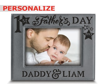 Puede incluir: Un marco de fotos gris con el texto "1st Father's Day" y "Daddy & Liam" grabado. El marco contiene una foto de un padre besando a un bebé. La palabra "Personalizar" está en la esquina superior izquierda.