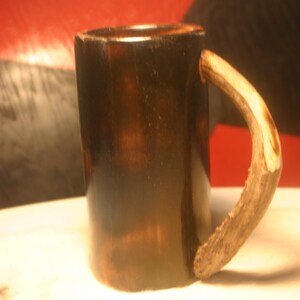 May include: A dark brown wooden mug with a light brown antler handle.