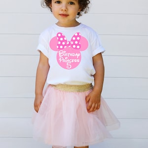 May include: A white t-shirt with a pink Minnie Mouse head design featuring white polka dots. The shirt says "Birthday Princess 5" in pink letters.