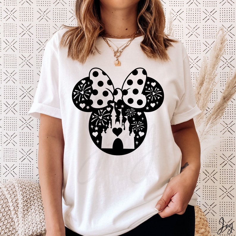 May include: White t-shirt with a black silhouette of Mickey Mouse ears with a bow and a castle inside. The bow has white polka dots and the castle has fireworks and hearts around it.