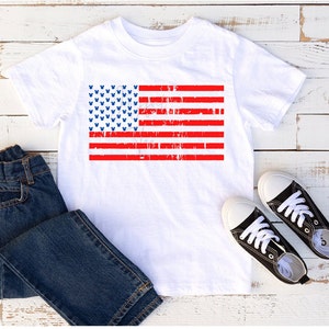 May include: White t-shirt featuring a distressed American flag design with blue Mickey Mouse heads. The flag is red, white and blue.