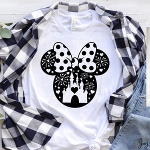May include: White t-shirt with a black silhouette of Mickey Mouse ears with a bow and a castle inside the ears. The bow has white polka dots. The castle has a heart in the center. There are fireworks and stars around the castle.