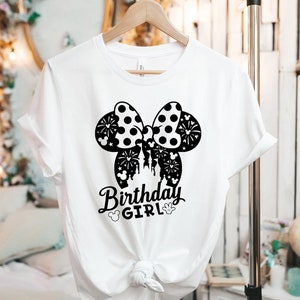 May include: White t-shirt with a black and white Minnie Mouse ears design and the text "Birthday Girl".