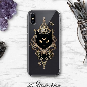 Peut inclure: Une coque de t&eacute;l&eacute;phone transparente avec un motif de silhouette de chat noir. Le chat a un croissant de lune sur le front et est entour&eacute; d'un motif g&eacute;om&eacute;trique dor&eacute;. Le texte "25 Hour Day" est imprim&eacute; sous la coque.