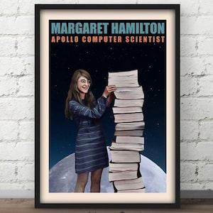 Puede incluir: Un póster enmarcado con una ilustración de Margaret Hamilton, científica informática de Apolo, de pie junto a una alta pila de libros contra un cielo estrellado oscuro y una gran luna. El texto dice MARGARET HAMILTON APOLLO COMPUTER SCIENTIST.