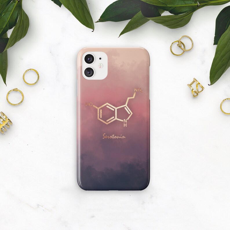 May include: A smartphone case with a gradient design in shades of pink, purple, and blue. The case features a gold-colored serotonin molecule graphic and the word "Serotonin" in a matching gold font.