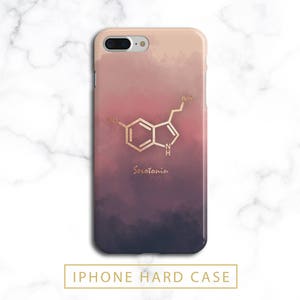May include: An iPhone hard case with a watercolor gradient of pink, purple, and dark blue. The case features a gold-colored serotonin molecule design and the word "Serotonin" in gold script.