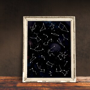 May include: A framed print of constellations on a black background with white lines and dots. The frame is silver with a decorative border.