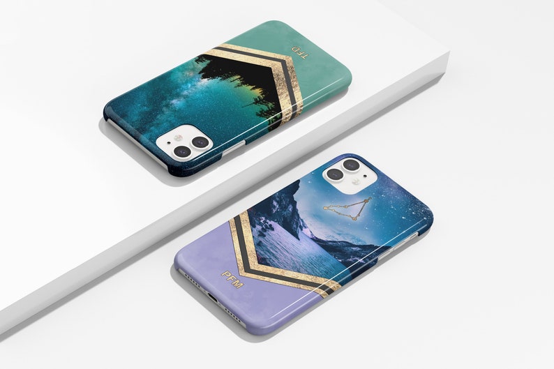 Peut inclure: Deux coques de t&eacute;l&eacute;phone avec une sc&egrave;ne de galaxie et de montagne. Les coques sont bleues, vertes et violettes avec des accents dor&eacute;s. Le texte "TED" et "PFM" est sur les coques.