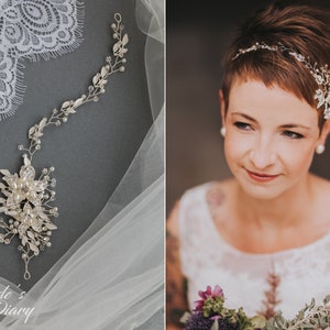 May include: A bride with short brown hair wears a delicate silver bridal headband with crystal and pearl accents. The headband is adorned with small leaves and flowers. The bride is holding a bouquet of flowers.