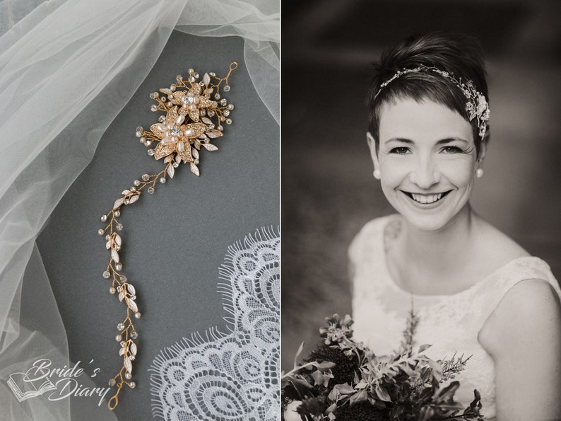 May include: A gold bridal hairpiece with delicate floral designs and sparkling crystals. The hairpiece is laid out on a white lace fabric and a gray surface. The hairpiece is designed to be worn in the hair, and it would be a beautiful addition to a wedding or other special occasion.