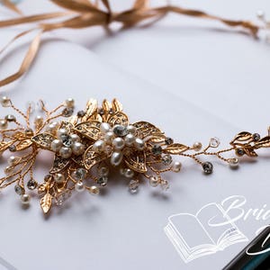 May include: Gold bridal hair vine with delicate leaves and pearl accents. The vine is adorned with a large floral design featuring gold and clear rhinestones.