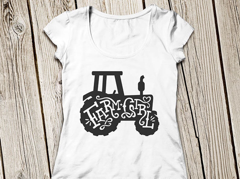 May include: White t-shirt with a black silhouette of a tractor with the words "Farm Girl" written inside the tractor.