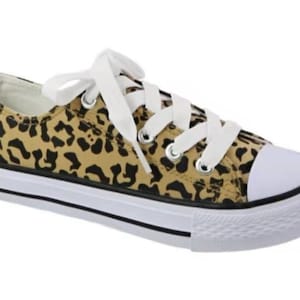 May include: A pair of low-top canvas sneakers with a leopard print design. The shoes have white laces and a white rubber sole.