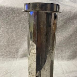 May include: A silver metal cylinder with a lid and a base. The cylinder has a slightly textured surface and appears to be used for making ice cream.