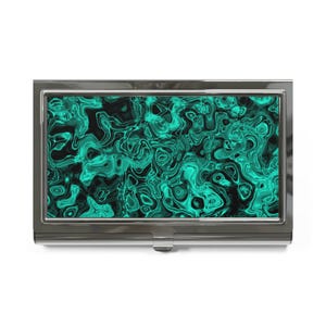 May include: A silver-coloured business card holder featuring a teal and black swirling pattern. The design is reminiscent of a gemstone or abstract art. The rectangular holder has a hinged opening. The pattern is a vibrant mix of colours.