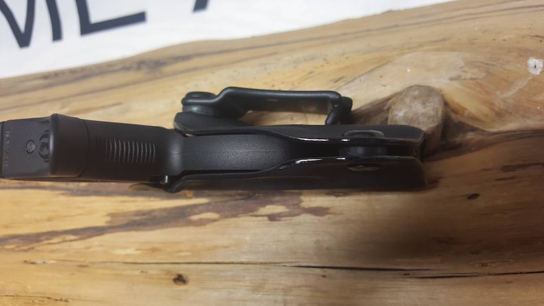 May include: A black gun holster with a built-in trigger guard. The holster is made of a durable plastic material and has a smooth, matte finish.