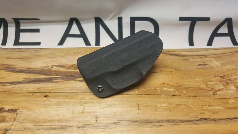 May include: A black leather holster for a firearm. The holster has a single screw on the front.