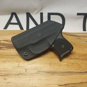 May include: A black leather holster for a small handgun. The holster is designed to be worn inside the waistband.