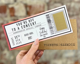 Könnte beinhalten: Ein pinkfarbenes und rotes Ticket mit dem Text "You're off to a concert..." Das Ticket ist für ein Konzert im Hammersmith Apollo in London am Montag, den 11. November 2024 um 19:00 Uhr. Das Ticket enthält auch den Text "Happy Birthday! Love Harriet XXX" und einen Rubbelbereich mit der Aufschrift "Scratch here to reveal surprise".