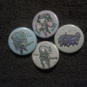 May include: Four round buttons with different cartoon characters. The buttons are light blue, light purple, light gray, and light green. The characters are a woman with blue hair, a man with a helmet, a man with a helmet and a gas mask, and a purple monster.