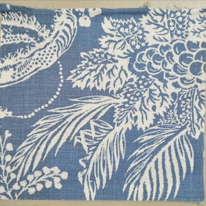 Può includere: Tessuto blu con un motivo floreale bianco. Il motivo presenta foglie, fiori e bacche.