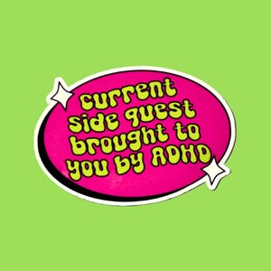 May include: A sticker with the text "current side quest brought to you by ADHD" in a retro font. The text is in yellow on a pink oval, outlined in white, with star accents, set against a green background.