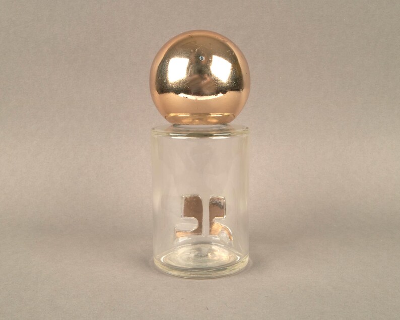 May include: A clear glass bottle with a gold-colored top and the number "35" printed on the front.