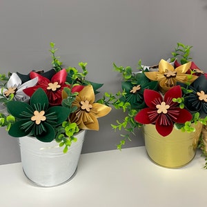 May include: Two metal buckets filled with paper flowers. The buckets are silver and gold. The flowers are red, gold, green, and white.