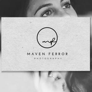 May include: A black and white business card with the text "MAVEN FERROR PHOTOGRAPHY" and a circular logo. The logo features the letters "mf" in a handwritten style. The card is set against a blurred background of a person.