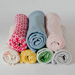 May include: A stack of rolled fabric swatches in various colours and patterns, including pink, blue, yellow, green, and grey.