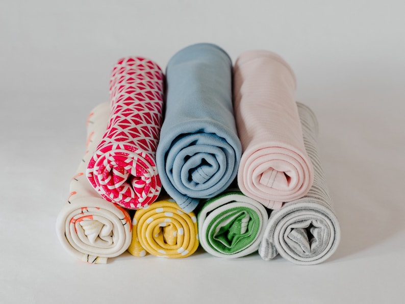 May include: A stack of rolled fabric swatches in various colours and patterns, including pink, blue, yellow, green, and grey.