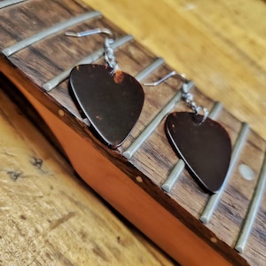 May include: A pair of earrings made from guitar picks, with silver hooks. The picks are brown and have a tortoiseshell pattern.