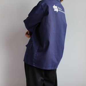May include: A navy blue work jacket with a white logo that says "Berliner Wasserbetriebe" and a white recycling symbol.