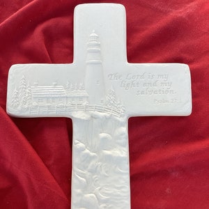 May include: White ceramic cross with a lighthouse and a house on a cliff. The cross has the text "The Lord is my light and my salvation. Psalm 27:1" on the right side.