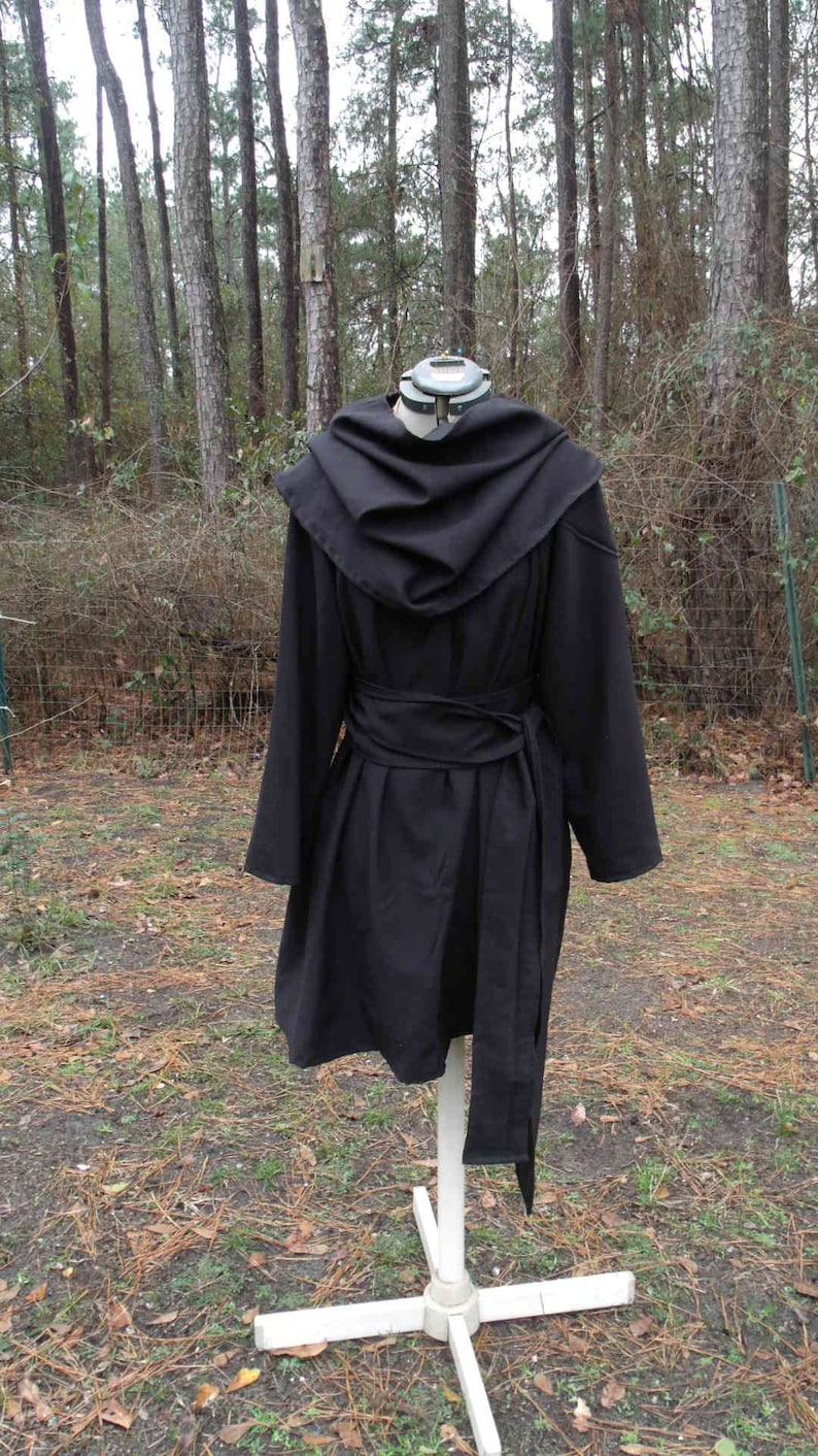 May include: A black hooded robe with a long, flowing design. The robe has a wide, gathered hood and a belt that ties at the waist.
