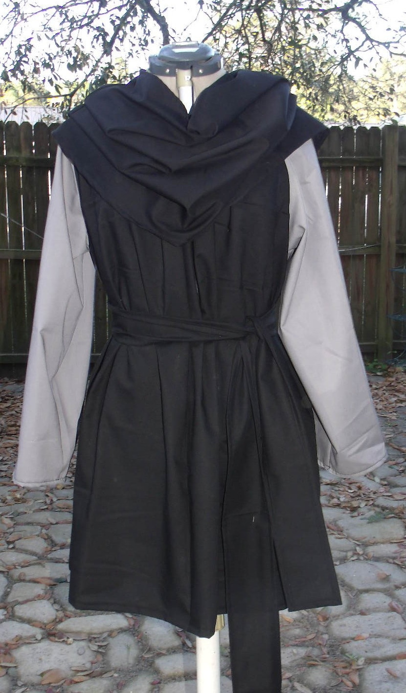 May include: A black hooded tunic with a long, flowing skirt and a cinched waist. The tunic has a gray underlayer and a black belt.