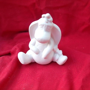 以下が含まれることがあります： 頭を下げて座っている漫画のロバの白いセラミック製フィギュア。フィギュアは未塗装で、装飾の準備ができています。