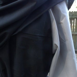 May include: A black hooded garment with a long, flowing sleeve. The garment is tied at the waist with a black sash.