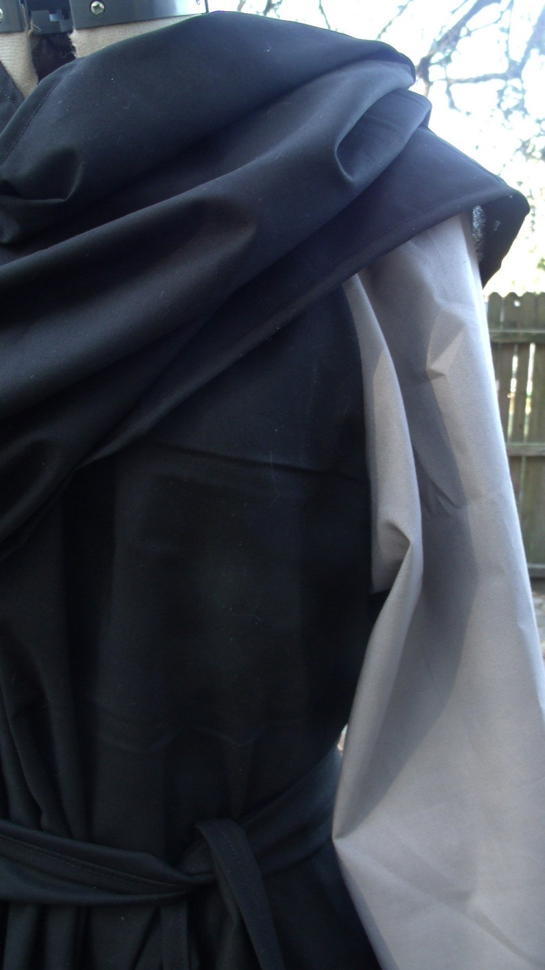 May include: A black hooded garment with a long, flowing sleeve. The garment is tied at the waist with a black sash.