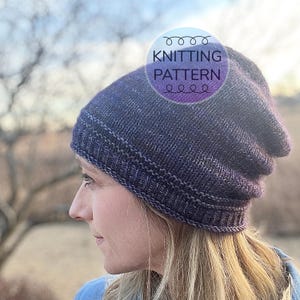 May include: A purple and gray slouchy beanie hat with a ribbed brim. The hat is knitted and has a subtle marled effect. The text "KNITTING PATTERN" is superimposed on the image.