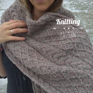 May include: A close-up of a gray knitted scarf with a cable knit pattern. The scarf is worn by a person and the text "Knitting Pattern" is visible in the image.